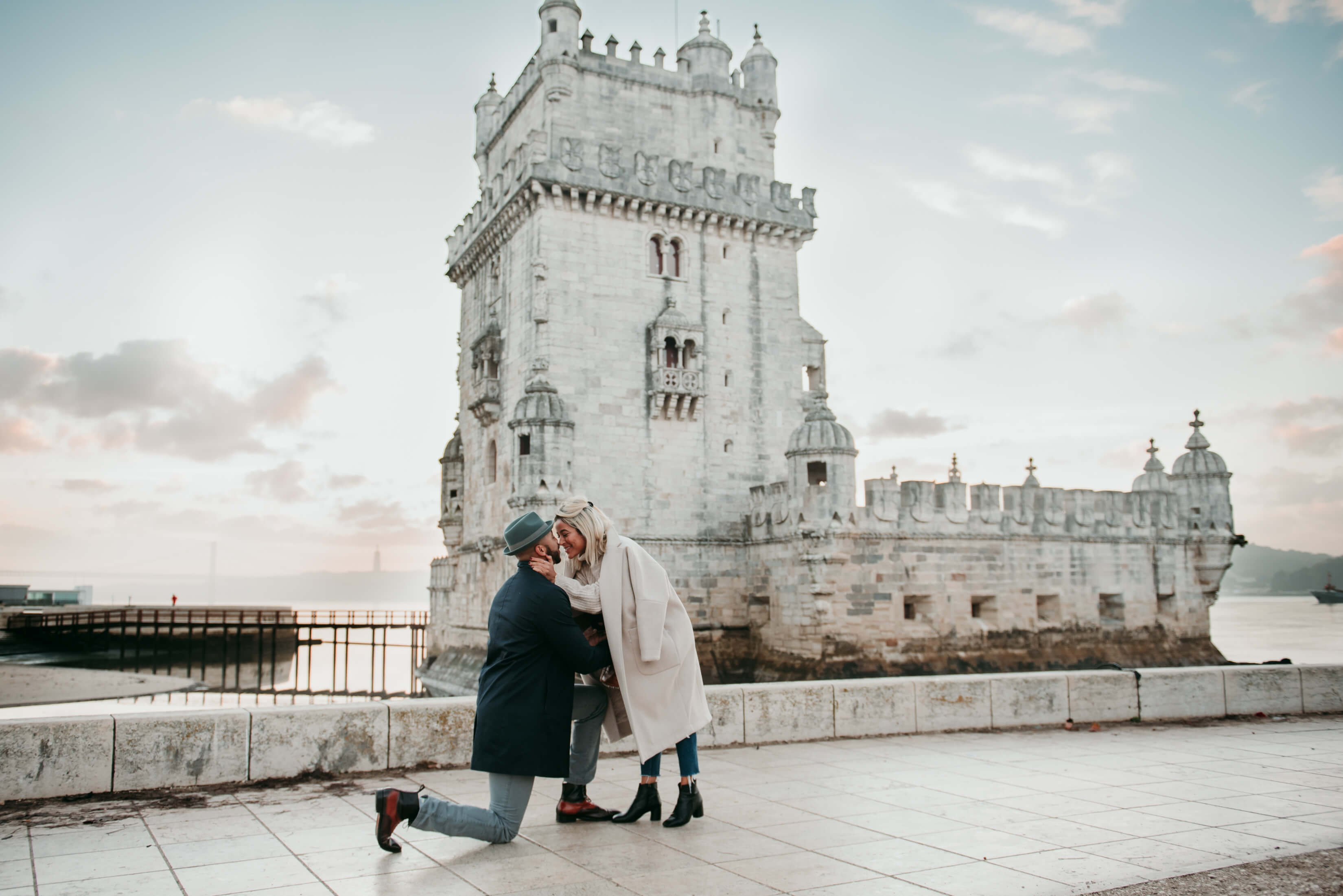 A couple mid-proposal in front of a tower in Lisbon
