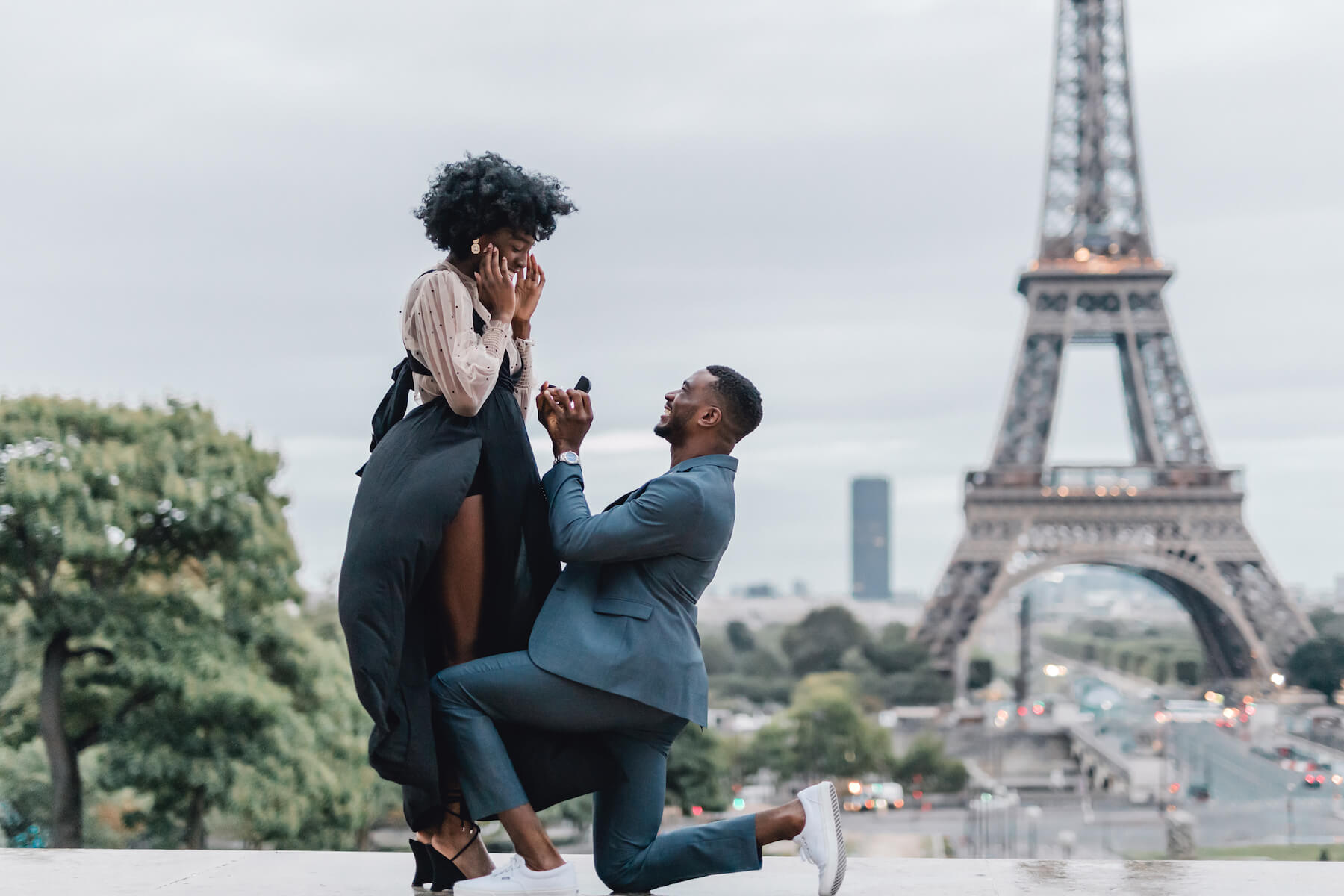 Man on one knee and surprised woman in front of the Eiffel Tower