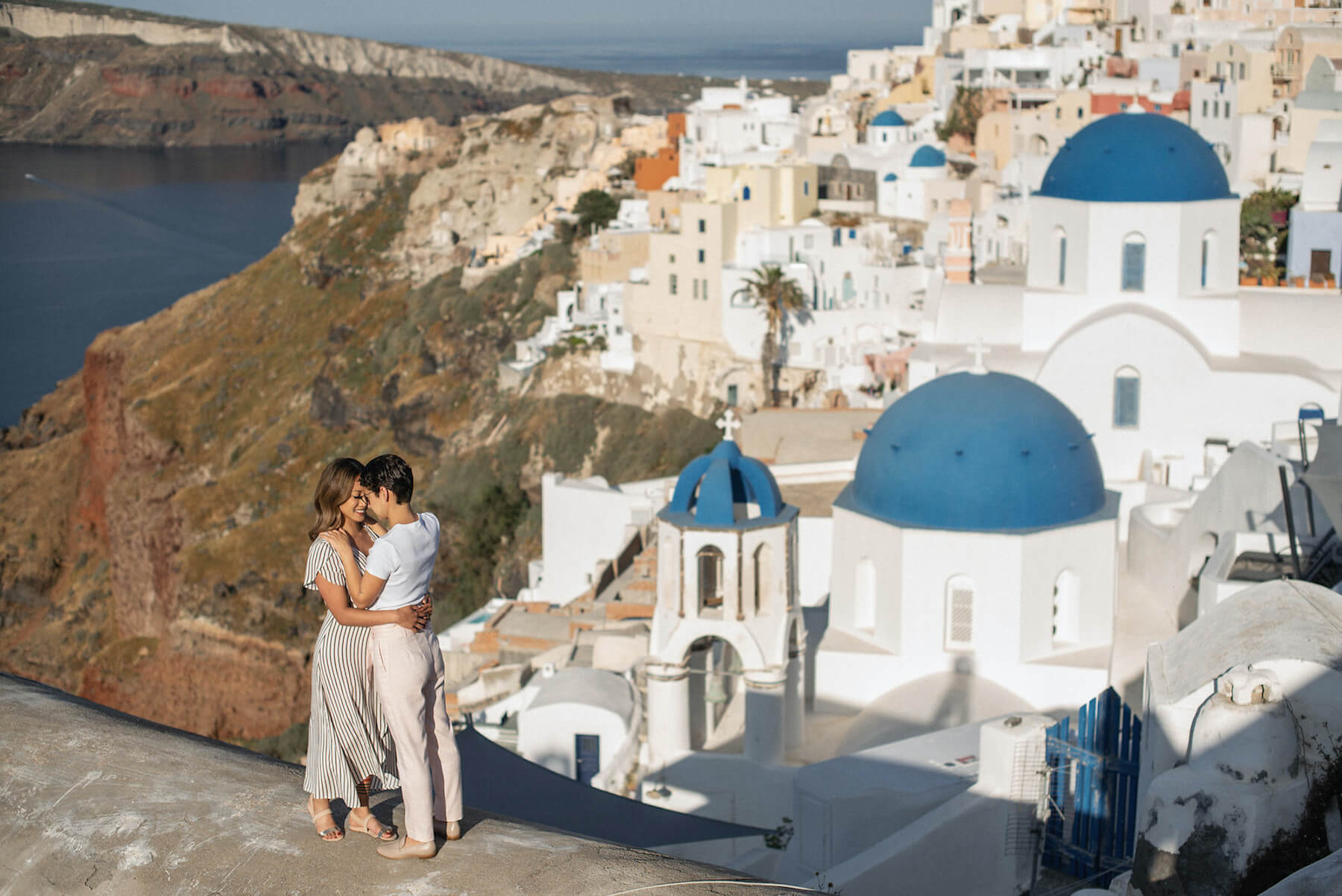 Couple enjoying the views surrounded by beautiful blue and white houses in Santorini